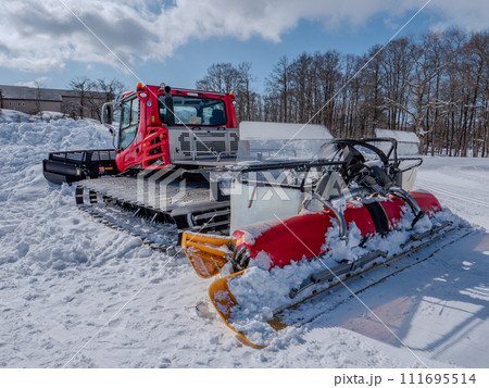 冬の青空と赤い圧雪車 111695514