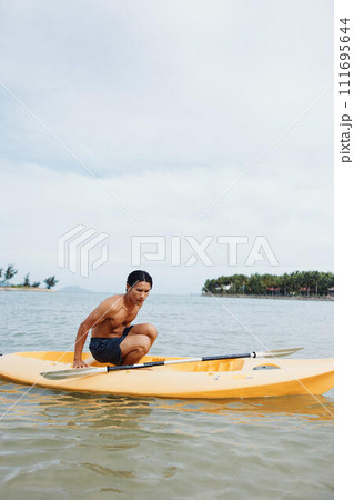 Happy Asian Man Kayaking in a Tropical Paradise Happy Asian Man Kayaking in a Tropical Paradise 111695644