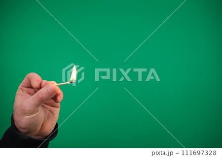 advertising Green background chromakey free space Lit matchstick held in hand by Caucasian male hand studio shot isolated. High quality photo advertising Green background chromakey free space Lit matchstick held in hand by Caucasian male hand studio shot isolated. High quality photo 111697328