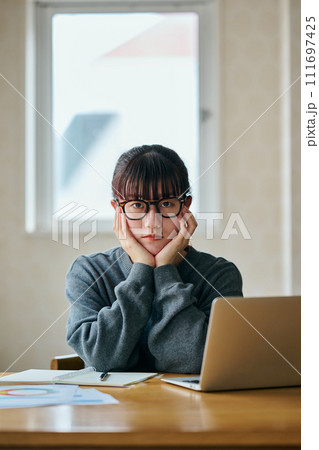 頬杖をついて考え事をするカメラ目線の若い女性 頬杖をついて考え事をするカメラ目線の若い女性 111697425