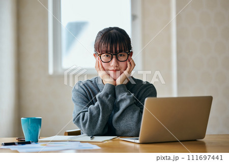 頬杖をついて考え事をするカメラ目線の若い女性 111697441