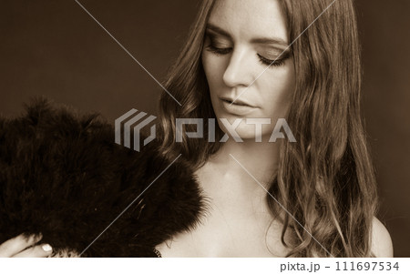 Woman holding carnival feather fan in hand. 111697534