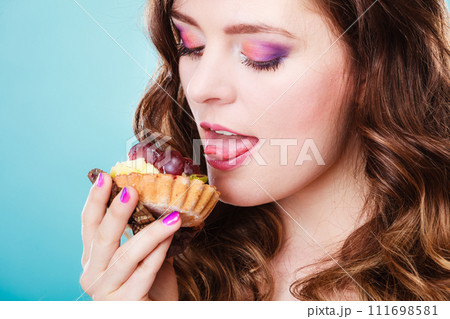 Cute girl holds fruit cake in hand on blue Cute girl holds fruit cake in hand on blue 111698581