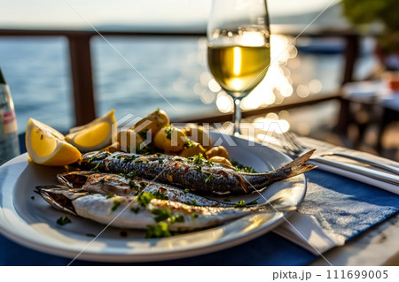 Grilled Sardines served in the restaurant at outdoor terrace with potatoes and glass of wine Grilled Sardines served in the restaurant at outdoor terrace with potatoes and glass of wine 111699005