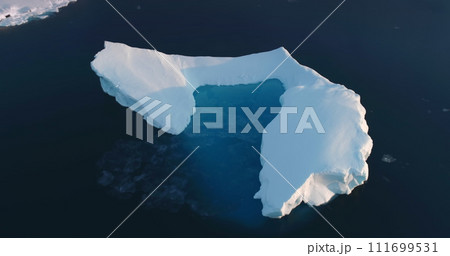 Melting Arctic iceberg aerial view. Glacier float in ocean water. Climate change and global warming problem. Polar nature environment. Wildlife North Pole winter landscape. Drone flight panorama Melting Arctic iceberg aerial view. Glacier float in ocean water. Climate change and global warming problem. Polar nature environment. Wildlife North Pole winter landscape. Drone flight panorama 111699531