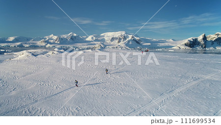 People running wild Antarctica snow trail race. Travel, active lifestyle, sport, recreation in Antarctic wild nature landscape. Snow covered mountains, icy ocean, sunny winter day. Aerial drone shot People running wild Antarctica snow trail race. Travel, active lifestyle, sport, recreation in Antarctic wild nature landscape. Snow covered mountains, icy ocean, sunny winter day. Aerial drone shot 111699534