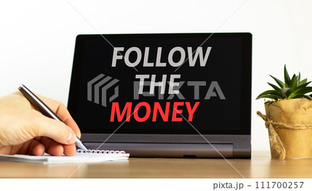 Follow the money symbol. Concept words Follow the money on beautiful tablet screen. Beautiful wooden table white background. Businessman hand. Business and follow the money concept. Copy space. Follow the money symbol. Concept words Follow the money on beautiful tablet screen. Beautiful wooden table white background. Businessman hand. Business and follow the money concept. Copy space. 111700257