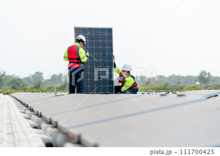 Professional technician worker sit and hold solar cell panel to check and maintenance also work with co-worker stand in front of the panel. Professional technician worker sit and hold solar cell panel to check and maintenance also work with co-worker stand in front of the panel. 111700425