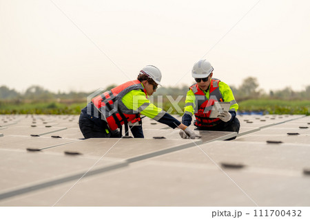 Close up of two technician workers sit and work on process of maintenance solar cell panel network system in concept of green energy power. Close up of two technician workers sit and work on process of maintenance solar cell panel network system in concept of green energy power. 111700432