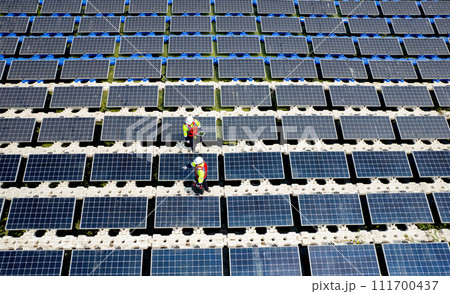Top view and wind shot of two technician workers maintenance or check system of solar cell panels over the water reservoir as solar farm factory in concept of green energy for good environment. Top view and wind shot of two technician workers maintenance or check system of solar cell panels over the water reservoir as solar farm factory in concept of green energy for good environment. 111700437