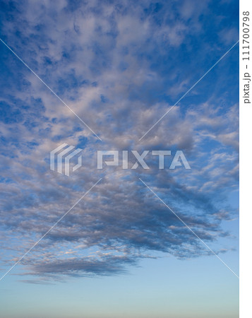 夕暮れの青空に夕陽に染まる白い雲が浮かんでる 111700798