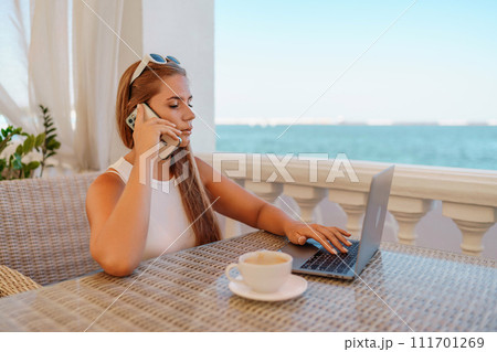 Woman coffee cafe macbook. Woman sitting at a coffee shop with mobile phone drinking coffee and looking away. Caucasian female relaxing at a cafe. Woman coffee cafe macbook. Woman sitting at a coffee shop with mobile phone drinking coffee and looking away. Caucasian female relaxing at a cafe. 111701269