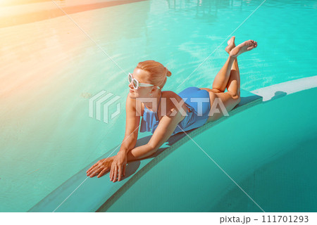 Bikini-clad woman enjoys poolside relaxation. Poolside ambiance. Capturing woman's relaxed time near pool. 111701293