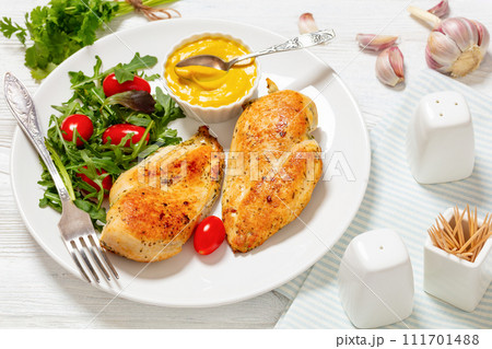fried chicken breasts with green salad on plate 111701488