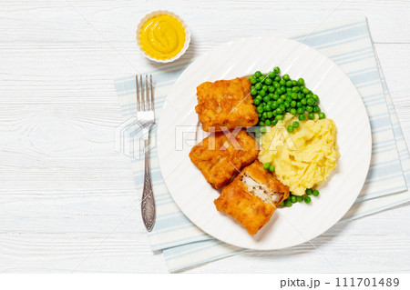 fried fish with mashed potatoes and green peas 111701489