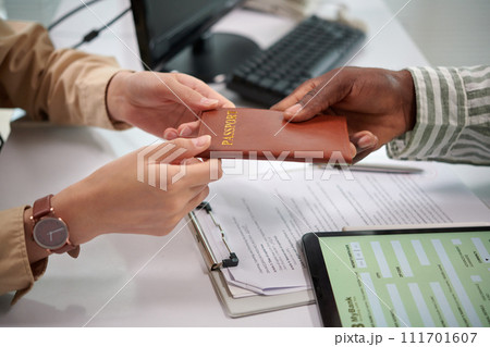 Bank manager returning passport to client after filling form for bank loan Bank manager returning passport to client after filling form for bank loan 111701607