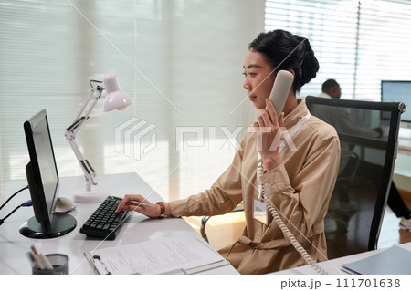 Bank manager talking to client on phone and filling document 111701638