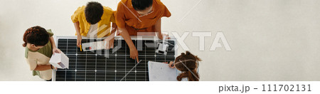 Header with teacher telling group of kids about renewable energy sources and showing solar panel and wind turbine 111702131