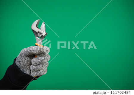a worker advertising Green background chromakey builder, repairman, handyman, hands with protection glove holding wrench on white background. High quality a worker advertising Green background chromakey builder, repairman, handyman, hands with protection glove holding wrench on white background. High quality 111702484