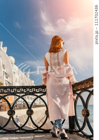 Woman summer travel sea. Happy tourist enjoy taking picture outdoors for memories. Carefree woman traveler posing on beach at sea on sunset, sharing travel adventure journey. Holiday vacation concept. Woman summer travel sea. Happy tourist enjoy taking picture outdoors for memories. Carefree woman traveler posing on beach at sea on sunset, sharing travel adventure journey. Holiday vacation concept. 111702486