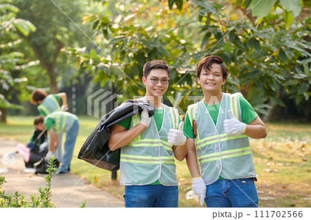 Smiling volunteers with garbage bags showing thumbs up 111702566
