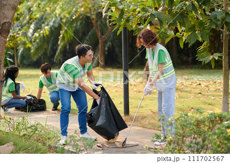 Young people volunteering in park, collecting garbage and fallen leaves Young people volunteering in park, collecting garbage and fallen leaves 111702567
