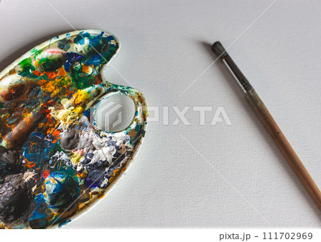 Palette with bright colours with paintbrush on white background. Abstract art. Paint palette with copy space. Drawing hobby. Mix of various colours. Creative design. Inspiration ideas. Vibrant texture 111702969