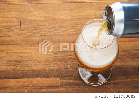 Pouring craft beer into pint glass on a wooden table Pouring craft beer into pint glass on a wooden table 111703085