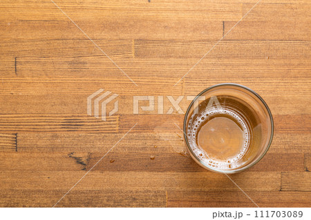 Nearly empty glass of beer with on wooden table Nearly empty glass of beer with on wooden table 111703089