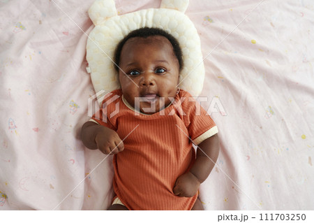 Portrait of Black newborn girl lying on bed with baby pillow, top view 111703250