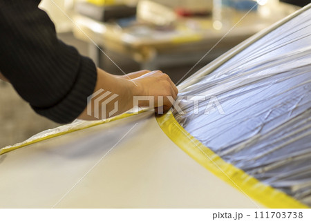 Applying masking tape to car bodywork. Applying masking tape to car bodywork. 111703738
