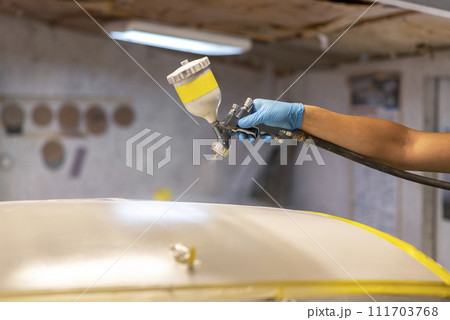 Man with protective clothes and mask painting car using spray compressor. Selective focus. 111703768