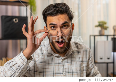 Amazed Indian businessman removing eyeglasses and looking at camera shocked wow expression good news 111704747