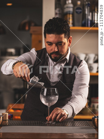 Barman putting ice cubes into glass 111704839