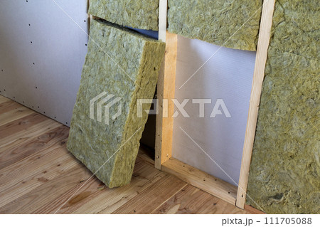 Wooden frame for future walls with drywall plates insulated with rock wool and fiberglass insulation staff for cold barrier. Comfortable warm home, economy, construction and renovation concept. Wooden frame for future walls with drywall plates insulated with rock wool and fiberglass insulation staff for cold barrier. Comfortable warm home, economy, construction and renovation concept. 111705088