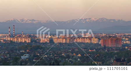 Wide panorama, aerial view of Ivano-Frankivsk city, Ukraine. Scene of modern tourist city with tall buildings, residential quarters and green streets on background of distant Carpathian mountains. 111705101