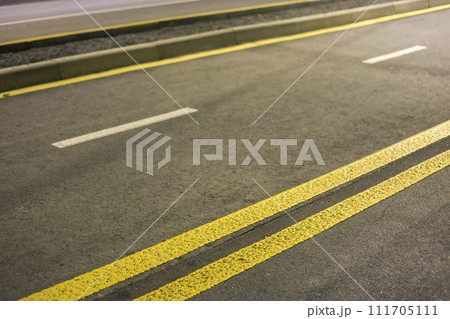 Wide bright yellow street marking sign line along modern wide smooth empty asphalt highway stretching to horizon. Speed, safety, comfortable journey and professional road building concept. Wide bright yellow street marking sign line along modern wide smooth empty asphalt highway stretching to horizon. Speed, safety, comfortable journey and professional road building concept. 111705111