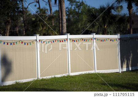 White vinyl picket fence on green lawn surrounding property grounds for backyard protection and privacy 111705115