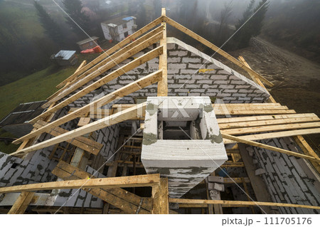 Top view of roof frame from wooden lumber beams and planks on walls made of hollow foam insulation blocks. Building, roofing, construction and renovation concept. 111705176