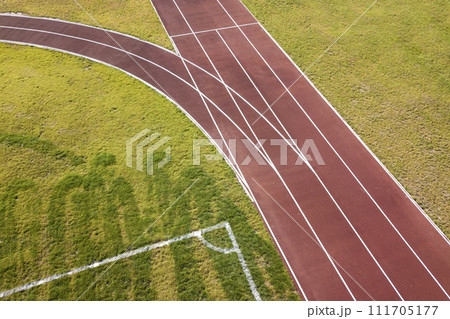Top view of red running tracks and green grass lawn. Infrastructure for sports activities. 111705177