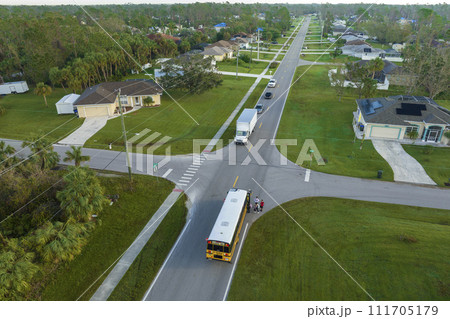 Top view of classical american yellow school bus picking up kids at rural town street stop for their lessongs in early morning. Public transport in the USA 111705179