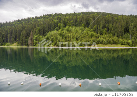Rope with white and yellow restriction markers on water surface for prohibiting of swimming in deep lake or sea. Rope with white and yellow restriction markers on water surface for prohibiting of swimming in deep lake or sea. 111705258