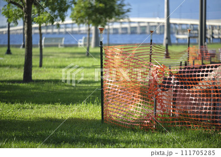 Restriction plastic mesh fence at industrial construction site. Protective barrier for pedestrians safety Restriction plastic mesh fence at industrial construction site. Protective barrier for pedestrians safety 111705285