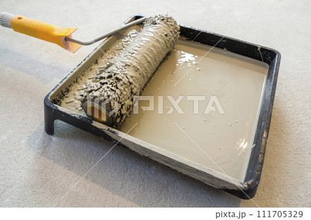 Paint roller in paint tray with grey color in the tray 111705329
