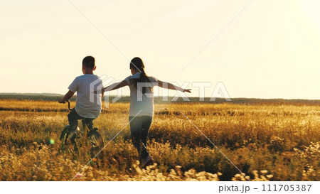 happy girl runs catching up with boy, child boy rides bicycle, son pedals, girl daughter plays airplane pilot, childhood dream airplane pilot fly, running sunset park, happy family kid, spinning wheel happy girl runs catching up with boy, child boy rides bicycle, son pedals, girl daughter plays airplane pilot, childhood dream airplane pilot fly, running sunset park, happy family kid, spinning wheel 111705387