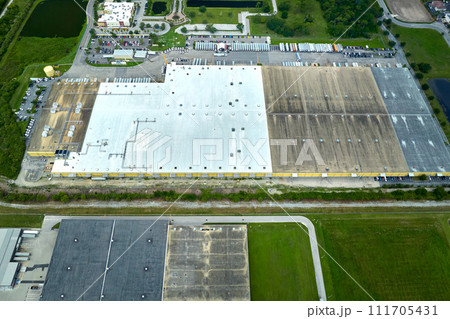 Large commercial distribution storehouse with many semitrucks unloading and uploading retail products for international shipment. Global market economy concept Large commercial distribution storehouse with many semitrucks unloading and uploading retail products for international shipment. Global market economy concept 111705431