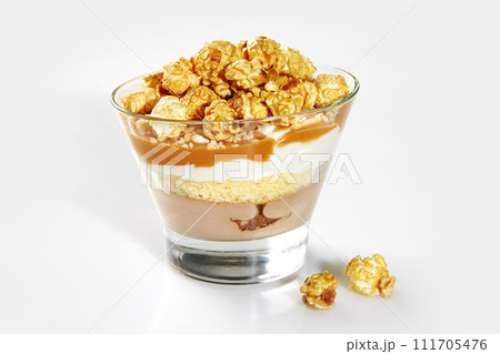 Layered trifle with sponge cake, caramel sauce and popcorn in glass Layered trifle with sponge cake, caramel sauce and popcorn in glass 111705476