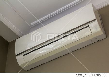 Cool air conditioner installed in room interior on white ceiling and light walls copy space background. Climate control, comfortable home concept. 111705639