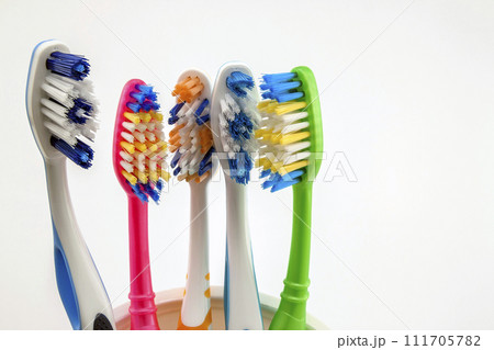 Close up shot of set of multicolored toothbrushes in glass on clean toilet on white background, concept dental. 111705782