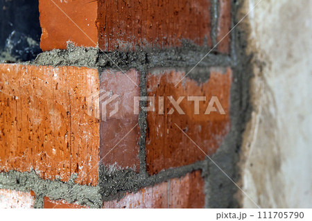 Close up of bricklaying industrial installing bricks on construction site wall Close up of bricklaying industrial installing bricks on construction site wall 111705790